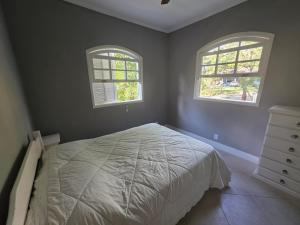 a bedroom with two windows and a bed at Sitio Mangalarga in Araras Petropolis