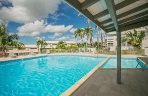 a swimming pool in a resort with palm trees at Rêve Marina studio tout confort avec citerne et piscine Gosier in Pointe-à-Pitre