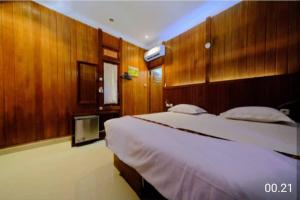 a bedroom with a large bed with wooden walls at Baron Ndut's Cottage in Mantaak