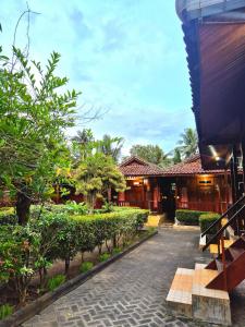 a walkway in front of a building with trees at Baron Ndut's Cottage in Mantaak +8 photos