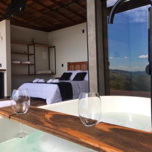 two wine glasses sitting on a bath tub in a bedroom at Shangri-lá Chalés in Gonçalves