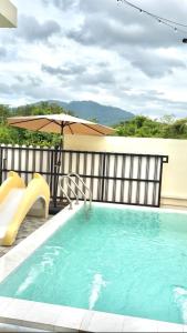 a swimming pool with a slide and an umbrella at MBP Pool villa เอ็มบีพี พูลวิลล่ายะลา in Changwat Yala