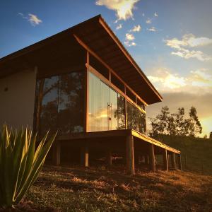 a house with large glass windows on a field at Shangri-lá Chalés in Gonçalves