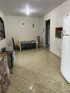 a kitchen with a table with chairs and a refrigerator at Casa do Cleber in Matinhos