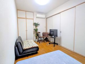 a living room with a black leather chair and a television at Apt熱海 in Atami