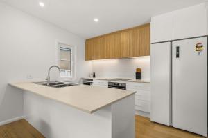 a white kitchen with a sink and a refrigerator at Blenheim Breeze by Experience Jervis Bay in Vincentia