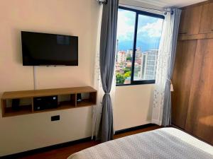 a bedroom with a flat screen tv and a window at Urban Escape Sky View in Cochabamba