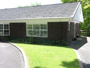a brick house with a green lawn in front of it at Woodhey Retreat Unit 2 in Karapiro