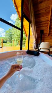 a person holding a glass of wine in a hot tub at Cabana Terra - Hidro com vista, Lareira e Café da manhã in Nova Petrópolis