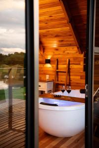 a bath tub in a room with two wine glasses at Cabana Terra - Hidro com vista, Lareira e Café da manhã in Nova Petrópolis