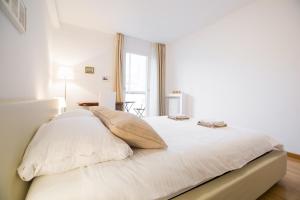 a white bedroom with a bed with white sheets and pillows at Apartman Kris in Zagreb