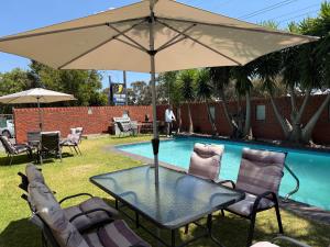 a table with an umbrella next to a swimming pool at Zero Inn Motel in Nhill