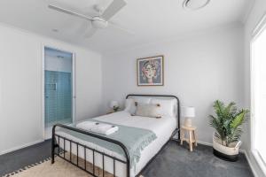 a white bedroom with a bed and a window at Lavender & Olive in Myrtleford