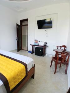 a bedroom with a bed and a table and a television at Nhi Quỳnh La Gi Hotel in Lagi