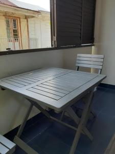 a picnic table and a chair on a balcony at Comme à la maison! Le Moule in Le Moule