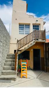 a house with a staircase and a orange chair in front of it at Estrellas del Sur in Río Gallegos