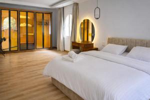 a bedroom with a large white bed and a window at Elegant Hydepark Apt With Garden in New cairo