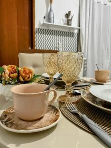 a table with a cup and plates and glasses on it at Royalties Flats in Petrolina