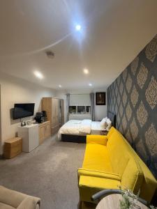 a bedroom with a yellow couch and a bed at Eastern Bridge House in Spinney Hill