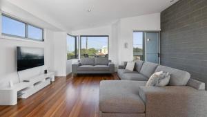 a living room with a couch and a flat screen tv at Beach Serenity in Sunderland Bay +7 photos