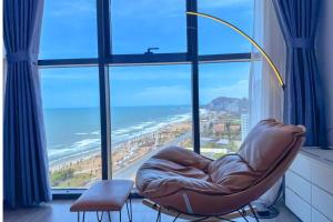 a chair in front of a window with a view of the ocean at CSJ Tower Seaview Apartment -Luxury Near Back Beach Vung Tau City in Vung Tau +63 photos