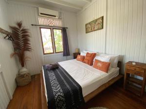 a bedroom with a bed with white sheets and orange pillows at The High Dive Gili Gede by Ultimate Resorts in Gili Gede