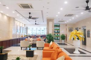 an office lobby with orange couches and chairs at HT Hotel in Xuyên Mộc