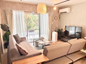 a living room with a couch and a television at Plus Life Shiraho A号室 in Ishigaki Island