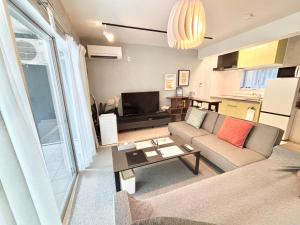 a living room with a couch and a table at Plus Life Shiraho A号室 in Ishigaki Island
