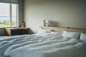 a bedroom with a large white bed with a window at SANU 2nd Home CURRENT Awajishima in Awaji