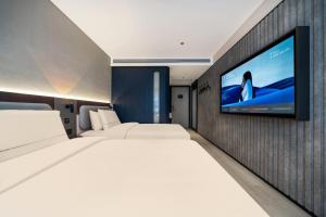 a bedroom with two beds and a tv on a wall at Atour X Hotel Chengdu Qingbaijiang Wanda in Chengdu