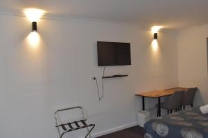a room with a bed a table and a tv on a wall at Belltower Motor Inn in Shepparton