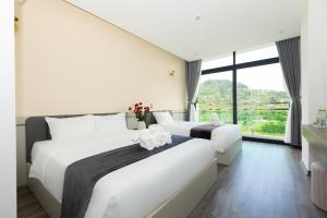 two beds in a room with a large window at NaCo Hotel in Lao Cai +39 photos