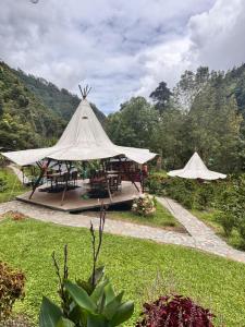 a tent with tables and chairs in a garden at Cabañas AlmA Rural Ibagué in Ibagué