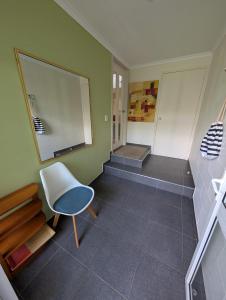 a room with a white chair and a staircase at Rainforest Cottage in Port Macquarie