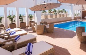 a pool with chairs and umbrellas next to a swimming pool at IntercityHotel Salalah by Deutsche Hospitality in Salalah