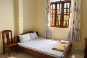 a bedroom with a bed and a chair and a window at Thanh Tâm Hotel in Can Tho