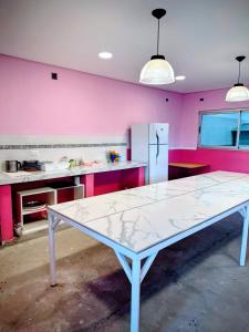 a white table in a kitchen with pink walls at Los Adobes in Cerrillos