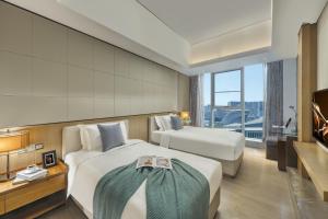 a hotel room with two beds and a large window at Ascott IFC Guangzhou in Guangzhou