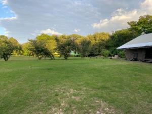 a large grass field with a building and trees at 4J's Cabins in Santa Familia