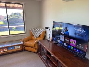 a living room with a large flat screen tv and a chair at Wilgra By The Beach in Wauraltee +5 photos