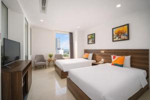 a hotel room with two beds and a flat screen tv at Mira Grand Hotel Quy Nhơn in Quy Nhon