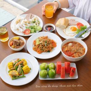 a wooden table with plates of food and drinks at Mira Grand Hotel Quy Nhơn in Quy Nhon