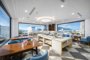 a restaurant with tables and chairs and large windows at Mira Grand Hotel Quy Nhơn in Quy Nhon