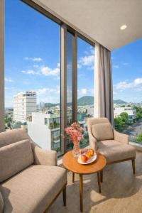 a living room with a table and chairs and large windows at Mira Grand Hotel Quy Nhơn in Quy Nhon
