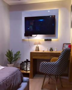 a bedroom with a desk with a television on a wall at Galaxy Blue sapphire Plaza Square Residency in Ghaziabad