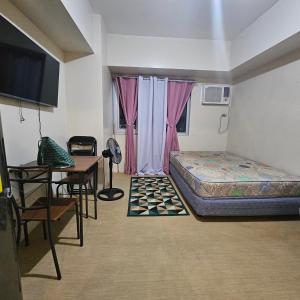 a bedroom with a bed and a table and a desk at Avida Davao condo Studio type in Davao City