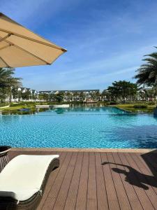 a swimming pool with a chair and an umbrella at CASA Villa NOVAWORLD Phan Thiet in Phan Thiet