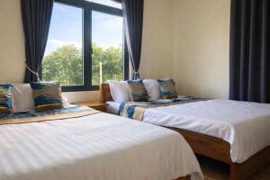 two beds in a room with a window at Hoàng Đô Hotel in Phú Quốc
