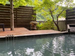 a swimming pool with a wooden deck and a bird bath at 旬樹庵　菊水 in Chikuma